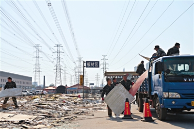 四惠建材市场，工人们将拆迁后剩下的商铺废墟清走。
